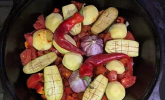 Remove the top peel from the garlic heads. Stick the heads into the vegetables. Peel, wash and distribute the potatoes whole in a cauldron. Cut the eggplants lengthwise and place them between the potatoes. Add a whole hot pepper. Don't forget to salt it.