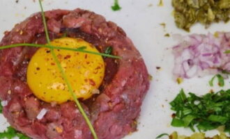 Let's start serving: lay out the beef as shown in the photo, make a small depression in the center and lay out the yolk. Place the finely chopped additives nearby.