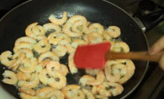 Boil pasta according to package instructions. Heat two tablespoons of olive oil in a frying pan, add shrimp and salt them a little.