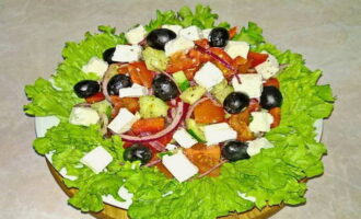 Servire la delizia in tavola, adagiandola su foglie di lattuga fresca e aggiungendo olive e cubetti di formaggio. La classica insalata greca con feta è pronta. Buon appetito!