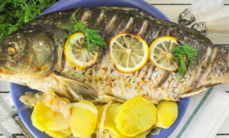 ¡La carpa al horno en el horno está lista! Transfiera el apetitoso plato al plato en el que planea servir la comida y decore con hierbas. Disfrute de una comida elegante. ¡Buen provecho!