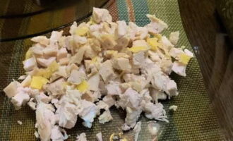 Trasferisci il pollo in un contenitore per assemblare l'antipasto. Sbucciare le uova dal guscio. Tagliate un uovo a cubetti e aggiungetelo al resto degli ingredienti.