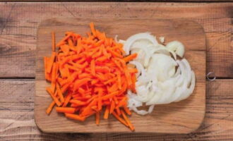 We peel the onions and carrots from the husks and peels, rinse them under water and let them dry. Next, cut the onion into thin half rings and grate the carrots. We spread the vegetables with the fish, which we first squeeze out of the released juice.