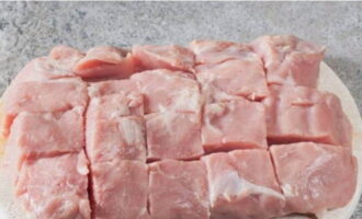 We cut the meat into large square segments and place them in a frying pan.