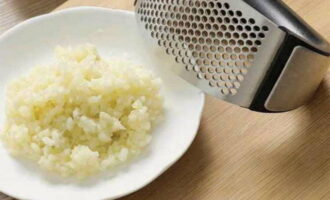 Peel the garlic cloves and press them into the fish mixture with vinegar.