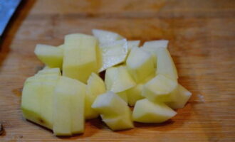 Retorne o caldo ao fogo, deixe ferver e acrescente as batatas descascadas e picadas aleatoriamente.