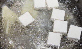 Fai bollire una pentola d'acqua e mettici dentro pezzi di tofu e germogli di bambù.