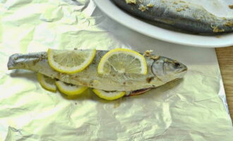 Læg fisken ovenpå, fyld indmaden med citron og læg skiverne ovenpå fisken.