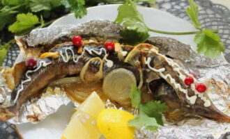 As soon as the fish is baked, place it on a plate directly in foil and decorate it to your liking, for example, with a mayonnaise mesh, berries and fresh lemon. Bon appetit!