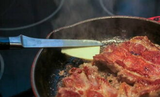 Remove the heat-resistant dish from the heat and add butter, as well as unpeeled garlic cloves, which we previously crushed with the edge of a knife.