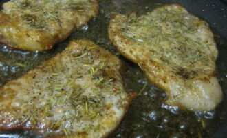 Add aromatic herbs to the meat and return the pan to the burner.