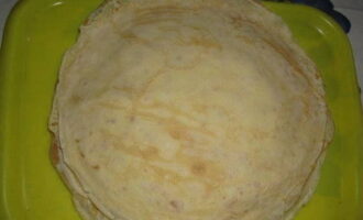 After 30 minutes, pour warm water into the dough and mix everything thoroughly. Fry thin ruddy pancakes in a frying pan.