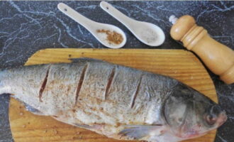 We make several oblique shallow cuts and rub the silver carp on all sides with spices and salt, sprinkle with citrus fruit juice and let soak for 20 minutes.