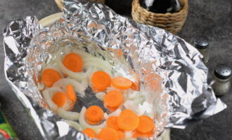 Take a heat-resistant pan of suitable size. Place a sheet of foil in it. Grease the foil with oil and arrange the carrot slices and onion rings.