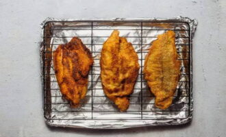 Transfira o peixe frito para uma gradinha, leve ao forno e cozinhe o bagre até ficar cozido. Este método de cozimento permite deixar o peixe o mais macio e suculento possível por dentro.