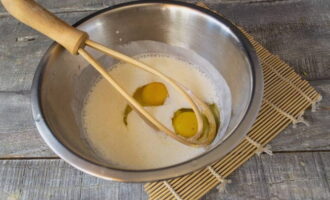 Pour fermented baked milk at room temperature into a deep bowl. Break chicken eggs here and add salt. Mix everything with a whisk.