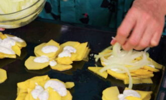 Cortar la cebolla en mitades. Coloca la mitad de la cebolla sobre las patatas.