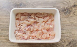 Rinse the meat and remove moisture with paper towels, cut into suitable pieces. I have fillet, but for juiciness it is permissible to use thigh flesh. Grease a baking container with vegetable oil and distribute the chicken meat. Add salt and pepper.