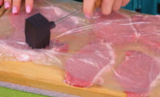 Place pork pieces on a cutting board. Cover the meat with cling film. Gently pound the pork on both sides with a mallet.