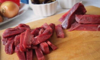 Lave a carne com água e corte em tiras bem finas.