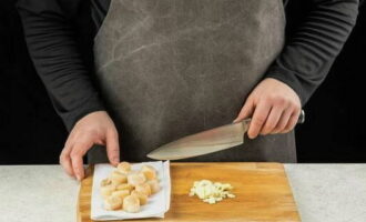 Pre-defrost the scallops, rinse them under water and dry them. Finely chop the garlic cloves.