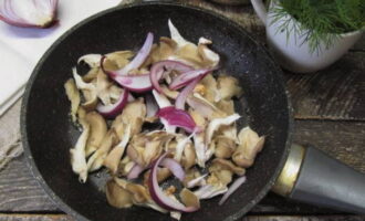 Wash the oyster mushrooms, remove all moisture with a napkin and divide the mushrooms into pieces. Cut the peeled onion into thin half rings. In another frying pan, heat a spoonful of vegetable oil, add chopped oyster mushrooms and onions to it and fry over high heat for 2 minutes.