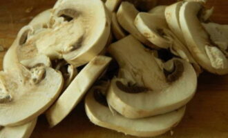 Sciacquare i funghi prataioli sotto l'acqua corrente, asciugarli con un tovagliolo e tagliarli a fette.