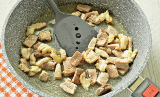 Fried potatoes with meat in a frying pan are very easy to prepare. You need to start by processing and frying the pork. Wash the meat and dry with paper napkins. Place the meat on a cutting board and cut into cubes. Pour a little oil onto the heated surface of the frying pan and fry the pork in it until golden brown.