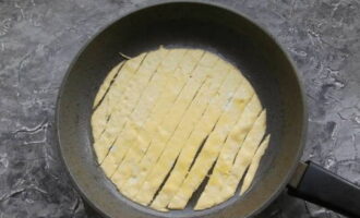 At the moment when the yolks have set, cut the mass into strips about two centimeters wide.