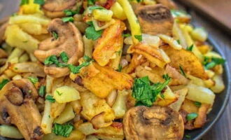 Fried potatoes with mushrooms and champignons in a frying pan are ready. Place on plates and serve!