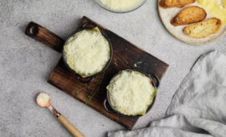 Espalhe fatias de queijo Emmental por cima do pão e polvilhe com queijo Gruyère ralado. Leve o prato resistente ao calor ao forno quente por 5-7 minutos até os queijos derreterem.