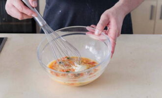 In a deep bowl, whisk the eggs and sour cream. Place the vegetables here and mix the contents.