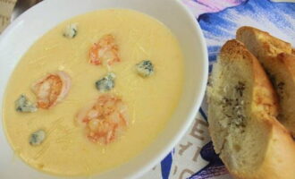 Pour the cream soup into bowls and top with shrimp and slices of blue cheese, and sprinkle with Parmesan cheese. Serve to the table and take a sample. Bon appetit! 