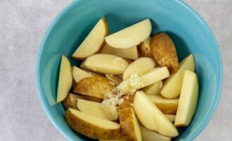 Do not peel the potatoes. Cut the tubers into thin slices and place in a large bowl. Peel the garlic cloves, then pass them through a press and add the resulting pulp to the bowl with the potatoes.