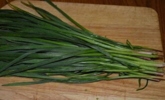 Die grünen Pfeile aus Knoblauch und Zwiebelfedern in kleine Stücke schneiden.