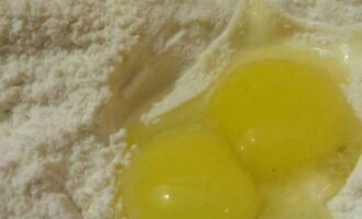 Sift wheat flour into a bowl for kneading dough and break two eggs into it.