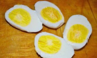 Lessare le uova di gallina finché sono teneri per 10 minuti, lasciarle raffreddare. Per fare questo, puoi metterli in acqua fredda. Successivamente sbucciamo i gusci e li tagliamo a pezzetti.