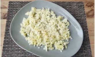 Die Kartoffeln schälen, auf einer groben Reibe hacken, in der ersten Schicht auf eine breite Salatschüssel legen und mit Salz und schwarzem Pfeffer bestreuen.