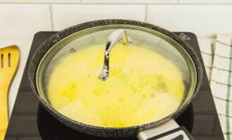 Cover the pan with a glass lid so that the frying process can be seen, and cook the omelette over low heat for 5-7 minutes. During this time, the omelette will rise, and the golden crust will only be on the bottom.