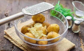 We schillen de teentjes knoflook en halen ze door een pers of hakken ze op een rasp en sturen ze naar de aardappelen.