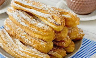 Πασπαλίζουμε τα churros με ζάχαρη άχνη, στοιβάζουμε σε μια πιατέλα και σερβίρουμε. Καλή όρεξη!