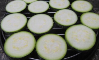 To bake zucchini casserole with cheese and tomatoes in the oven, first wash the zucchini and cut it into circles of equal thickness. Place them on a wire rack and bake in an oven preheated to 200 degrees for 20 minutes.