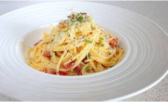 Divide carbonara pasta with bacon prepared according to the classic recipe into serving bowls, sprinkle with freshly ground pepper and serve hot. Bon appetit!