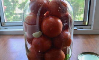 We wash and sterilize a three-liter jar. Place dill, garlic cloves and chili peppers on the bottom. Place the washed tomatoes tightly here.