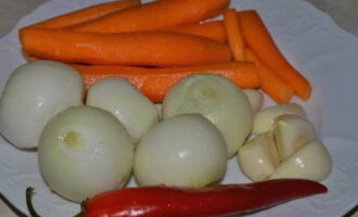 Sbucciare carote, cipolle e aglio. Laviamo le verdure insieme al peperoncino.