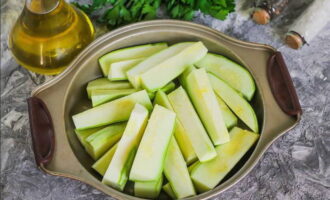 We wassen de courgette onder stromend water en snijden hem in grote blokjes. Bij jonge courgettes hoeven de schil en de zaden niet verwijderd te worden.Vet een ovenschaal in met plantaardige olie en leg de gesneden courgette erop.