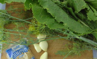 Peel the garlic, wash the dill branches and horseradish leaves.