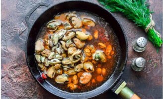 Gleichzeitig die Muscheln in kochendem Wasser 2-3 Minuten kochen und mit einem Schaumlöffel in die Pfanne geben.