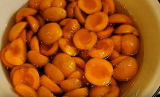 Place the apricot halves into the hot syrup and immerse them completely with a spatula. Leave the apricots to infuse in the syrup for 12 hours.