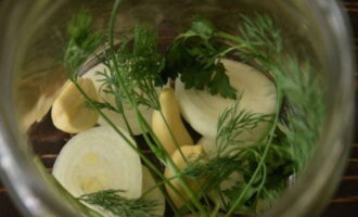 Place herbs, garlic cloves and onion pieces at the bottom of the prepared jars.